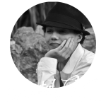 Voice Actor and Voice Director Crystal Storm. Black and White photo. Crystal is wearing a fedora, with her hand against her face, staring off into the distance.